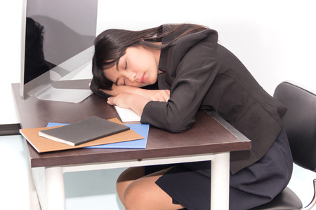 Working woman exhausted and sleeping on working deskの写真素材