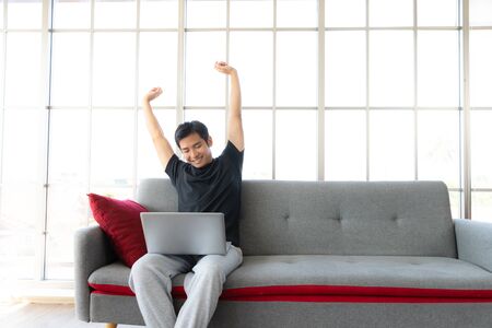 Asia man stretch oneself lazily while working with laptop, work from home conceptの写真素材