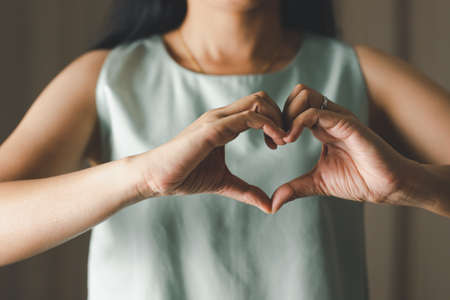Close up of woman making heart shape for Valentines day, Mothers day and Breast Cancer Awareness month for Healthcare of International Women dayの写真素材