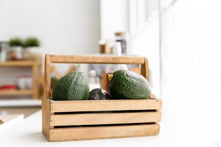 Avocados fruit in wooden basket in the kitchen. Healthy food.の写真素材