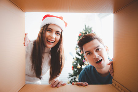 Young couple opening a Christmas present and looking inside the box, view from inside of the box