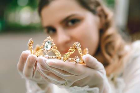 Beautiful woman in vintage gloves. Crown diadem in hands. Elegant ladyの写真素材