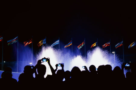 People shoots fountain and flags on smartphones. People silhouettes. Night