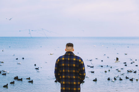 Young men by the sea. Swans seagulls. Cold weather.