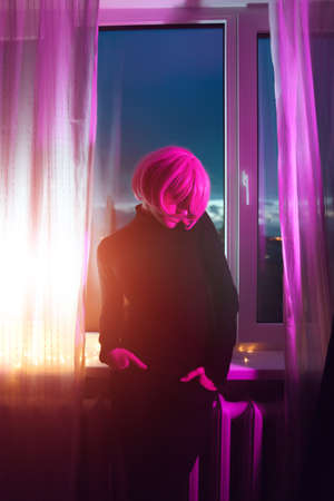 Fashion woman pink hair near the window. Pink light. Life style.の写真素材