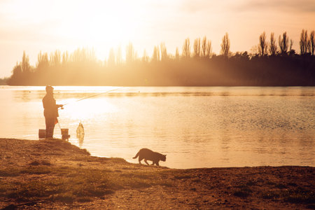 Fisherman with a fishing rod on the river bank
