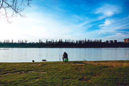 Fisherman with a fishing rod on the river bankの写真素材