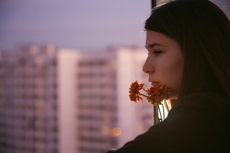 Young natural beauty long hair girl with flowers on the balcony. Spring. Evening. High-rise area....