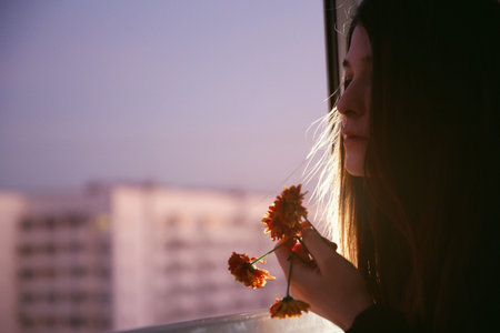 Young natural beauty long hair girl with flowers on the balcony. Spring. Evening. High-rise area....