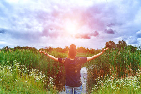 Holiday in the spring. Girl in the sun on nature. Beautiful cloudsの写真素材