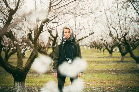 blonde girl with a camera in the blossoming apricot trees. White flowers. Spring. photographer