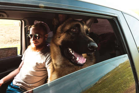 Man in glasses and Dog sitting in a car Outdoor Lifestyle Travel Friendship concept nature on backgroundの写真素材
