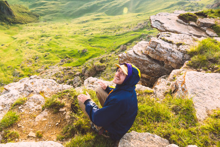 Young Man sitting alone outdoor green valley mountains on background Travel Lifestyle and survival conceptの写真素材