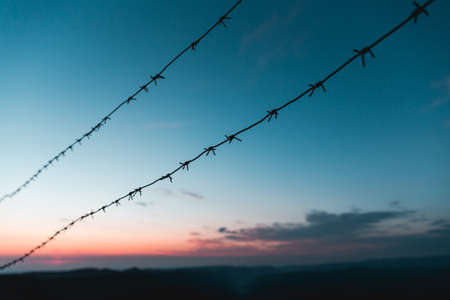 Barbed wire on the background of the sunrise in the mountains. Early morning purpleの写真素材