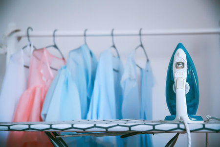 Modern iron and clothes in dry-cleaning salon