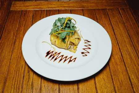 pancake with stuffing. Arugula. On a white plate on a wooden tableの写真素材