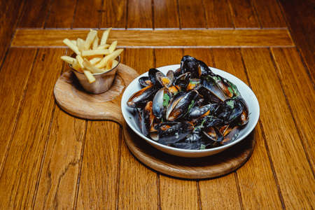 fried mussels in shell and french fries on a wooden tableの写真素材