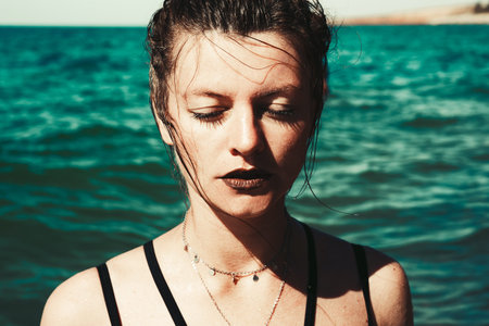 Beautiful attractive girl with closed eyes on the beachの写真素材