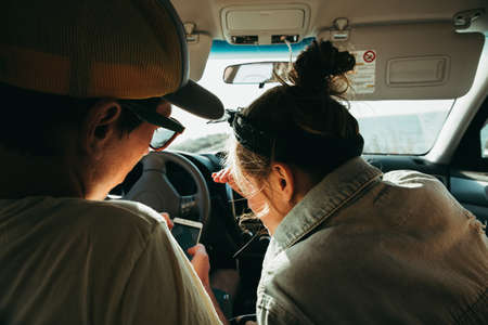 The couple decides where to go. They look at the phone. Navigation. In the car during travel summer holidays vacationの写真素材