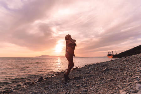 Young girl with tattoo posing at sunset sea. Vacation.の写真素材