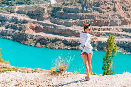 A slender girl in a white shirt dancing alone by the sandy career. Against the background of mountains and a blue azure lake. Georgia landscapeの写真素材