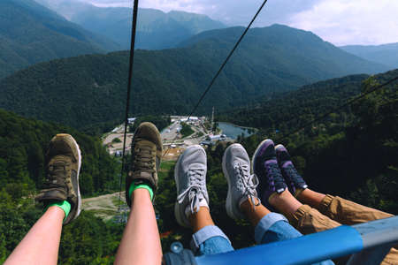 Three girlfriends sitting in a ski lift elevator. Feet Selfie. Mountains travel concept.の写真素材