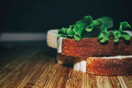 Two pieces of white bread and a leaf of lettuce on a wooden board. Kitchen theme. Healthy eating. Veganismの写真素材