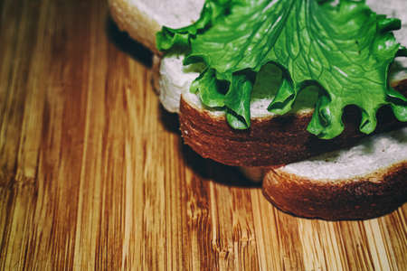 Two pieces of white bread and a leaf of lettuce on a wooden board. Kitchen theme. Healthy eating. Veganismの写真素材