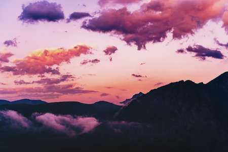 Purple-pink sky with clouds over the silhouette of the Caucasus Mountains Sunset landscapeの写真素材