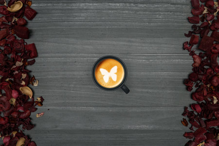 Simple wooden planks background, black coffee cup, patterned milk foam and dry red leaves on sides