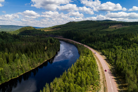 High angle aerial view of river and road running through forest and mountainous landscape in...