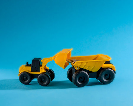 yellow toy truck and bulldozer loading coins. space for text.