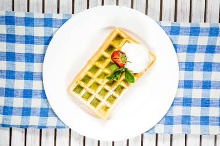 Plate of belgian waffles with ice cream, caramel sauce and fresh fruitの写真素材