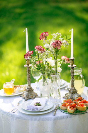 beautifully laid a festive table for two in the garden with flowers and candles