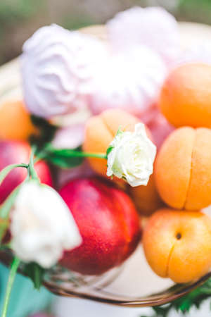 Ripe peaches in in a glass bowl for fruits on the table with marshmallowの写真素材