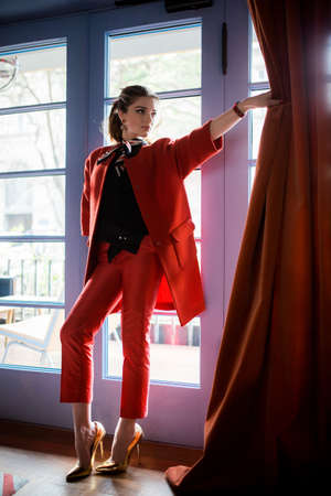 beautiful young and stylish Successful business woman in a red suit looking confident and smilingの写真素材