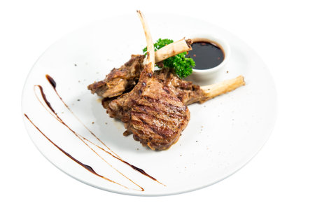 Roasted lamb ribs with spices and garlic on the white containers with the sauce