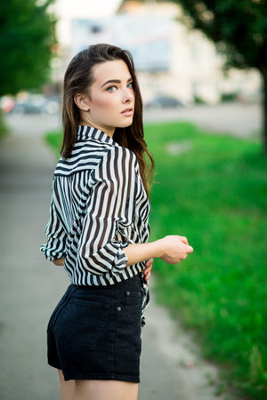 Outdoor summer portrait of young pretty cute brunette girl. Beautiful woman posing in spring.の写真素材