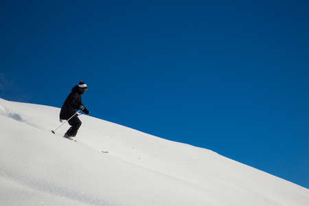 Male skier skiing in fresh snow on ski slope on a sunny winter day at the ski resort in Georgiaの写真素材