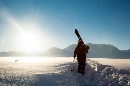 male skier carries skis in the snow on winter day at the ski resort in Georgiaの写真素材