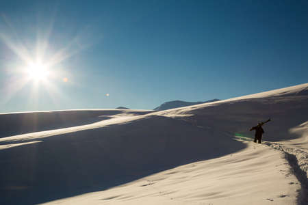 male skier carries skis in the snow on winter day at the ski resort in Georgiaの写真素材