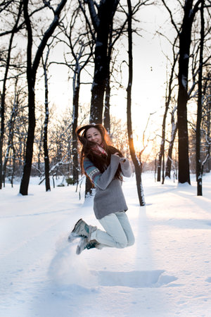 attractive young woman (Girl) playing with snow in warm clothing smiling in the Park