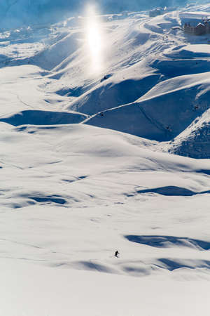 Male skier skiing in fresh snow on ski slope on a sunny winter day at the ski resort in Georgiaの写真素材