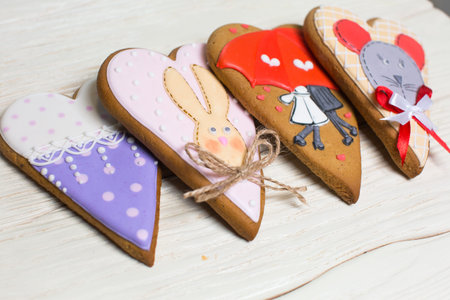 a collection of gingerbread cookies in the shape of a heart, muffins and animals on a white wooden backgroundの写真素材