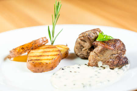 Beautiful juicy grilled meat with fried potatoes on a wooden tableの写真素材