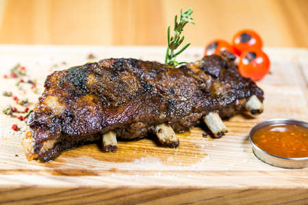 Roasted lamb ribs with spices and garlic on the wooden background with the sauceの写真素材