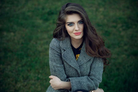 beautiful brunette girl in dress and coat. Model posing outdoorsの写真素材