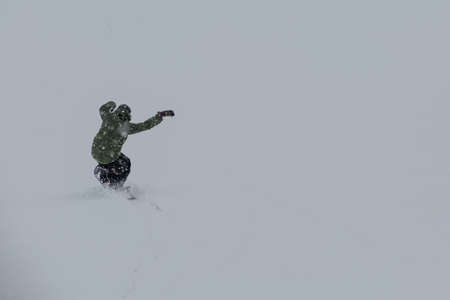 Male snowboarder snowboarding on fresh snow on ski slope on Sunny winter day in the ski resort in Georgiaの写真素材