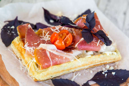 Belgian waffle with sauce, cured meat, Parmesan cheese, Basil and cherry tomatoesの写真素材