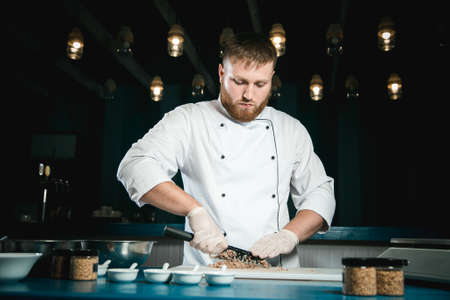 Cheerful bearded chef cook cooking while cooking meals in the kitchenの写真素材